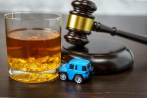 A toy car with a gavel and a glass of alcohol. You can find out how long a DUI stays on your record with legal professionals.