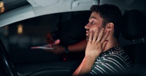 Stressed man in the driver’s seat of a parked car wondering about what happens when you get a DUI in WA.