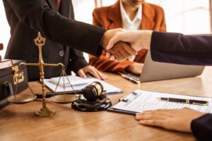 Two people shaking hands at a conference table. Learn about the average wrongful death settlement amount.