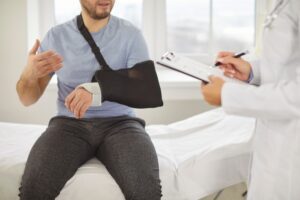 A man with his arm in a sling consulting a doctor. Learn about when it’s too late to go to the doctor after an accident.