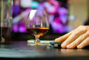 A man reaching for car keys with a glass of whisky in the background.  